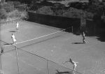 Long shot of a tennis court with four people playing tennis. Playing Tennis, Circa 1955