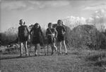 Long shot of four children standing outside, two are using crutches with legs in plaster trees in the background. Smiling for the Camera, Circa 1955