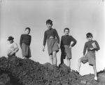 Long shot of one adult and four children standing outside on a dirt mount posing for the camera. Posing on the Rocks, Circa 1955