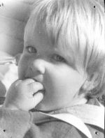 Close shot from the side of the face of a young child sucking their hand. Portrait of a Child, Circa 1955
