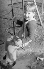 Medium shot from the side of a young child sitting on a swing. Play Time, Circa 1955