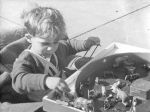 Medium shot of a young child sitting at a play table that has animal figurines of elephants, cows, horses. Play Time, Circa 1955