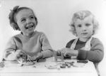 Medium shot of two young children sitting at a small table playing with wooden toy letters. Play Time, Circa 1955
