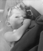 Close shot of a young child lying cuddling a blanket and sucking a thumb. Portrait of a Child, Circa 1955