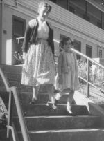 Long shot taken outside from below of a woman and child walking down some concrete steps. On the Steps, Circa 1955