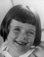 A close up shot of a young child smiling for the camera. The child has 'page boy' style haircut. Portrait of a Child, Circa 1955