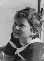 Medium shot of a child seated with braces fitted over shoulder and chest looking to the side posing for the camera. Portrait of a Child, Circa 1955