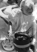 A close up shot of a young child cutting a birthday cake. Child looks to be holding a knife in right hand. Child is wearing a hat. Enjoying Birthday Cake, Circa 1955