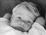 A close up shot of a young child lying back with his arms behind his head. Portrait of a Child, Circa 1955