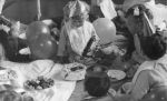 A close up shot of six young children sitting at a party. Four children are wearing party hats; balloons, a birthday cake & food in bowls are visible. Child facing the camera in the group is holding a toy bus. Birthday Celebrations at the Hospital, Circa 1955