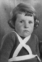Medium shot of a child seated with braces fitted over shoulder and neck posing for the camera. Portrait of a Child, Circa 1955