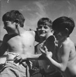 Medium shot of three children standing outside one child has a brace from waist to chest, posing for the camera. Children Playing, Circa 1955