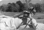Medium shot of a young person outside bandaged lower body laying supine on a mattress, wearing glasses binoculars are held to eyes posing for the camera. Binoculars, Circa 1955