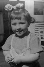 Medium shot of a child standing outside a ward holding a toy posing for the camera. Portrait of a Child, Circa 1955