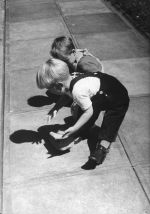Medium shot of two small children playing outside on a footpath. The one in the foreground has a leg brace. Playing Outside, Circa 1955