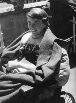 Medium shot of a young patient sitting outside in a wheelchair, wrapped in a blanket. Patient in Wheelchair, Circa 1955