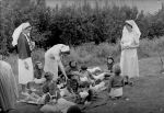 A long shot of a group of young patients lying outside in the garden on rugs. Some of the children are eating fairy floss, some have casts on their legs. They are being watched and helped by three nurses. Picnic on the Lawn, Circa 1955