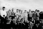 A long posed shot of a group of fifteen men. Half are standing while the others are squatting in front. There is also a child kneeling in front. Uncle Bobs Club, Circa 1955