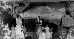 A long shot of three young women on stage dressed in costume. There are other children sitting on the stage in the background, also in costume. Pantomime at the Hospital, Circa 1955