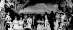 A long shot of a group of people and children posing for the photograph, sitting and standing on a stage dressed in costumes. Pantomime at the Hospital, Circa 1955