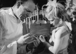 Close up shot of a medical staff member taking blood from the thumb of a young child. He has a long tube in his mouth that extends to the child's thumb. Blood Tests, Circa 1955