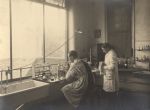Two doctors working in a Pathology Laboratory. Bunsen burners, vials, bottles and other instruments can be seen on benches and shelves. Pathology Lab, 1923-1924