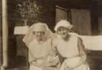 Medium shot of two staff members, one staff member is holding a baby. Nurses Smiling and Holding a Baby, 1922
