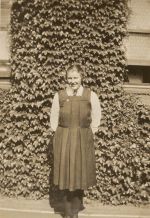 Long shot of adult standing in front of garden wall. Young Female in School Uniform, Circa 1922