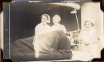 Medium shot of three staff members and one patient lying in a bed. Nurses with Patient, Circa 1941