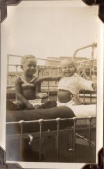 Medium shot of two young children sitting up on a bed. Exterior of buildings can be seen in the background. Patients in Bed, Circa 1941