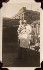 Long shot of Staff holding a young child. A cot and buildings are in the background. Medical Staff and Patient, Circa 1941