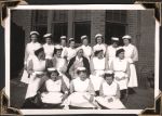 Long shot of sixteen staff members arranged in three rows. They are outside a brick building. Staff Portrait, Circa 1945
