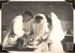 Medium shot of three hospital staff in uniform: one male and two female attending to a child patient who lies on a bed. The child has bandages on their legs. Treating a Patient, Circa 1945