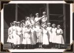 Long shot of a group of staff members standing outside a brick building. They stand under a verandah and some are standing on a short staircase. Staff Portrait, Circa 1945