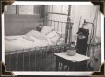 Long shot of a patient room with a young child lying in bed, under the covers, looking out the window. He wears an oxygen mask attached to a tank of gas. Small Child on Oxygen, Circa 1945