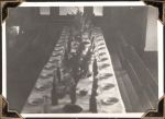 Long shot of a room with a long table set with plates, bottles and flowers. The photograph is taken from the head of the table. Nurses' Christmas Dinner, Circa 1945