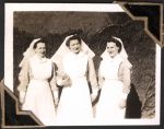 Medium shot of three staff members, taken outside, standing in front of a vine covered wall. The staff member in the middle is holding a book in her right hand. Three Nurses, Circa 1945
