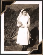 Long shot of a staff member standing outside, in front of vine covered wall, holding a book in her right hand. A Nurse, Circa 1945