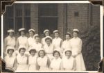 Medium shot of fifteen staff members, standing in front of a building. Staff Portrait, Circa 1945