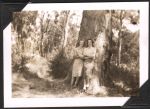 Long shot of two women in casual dress standing against a tree with bush scenery in the background. Outside Enjoying Nature, Circa 1945