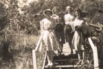 Long shot of four women in casual dress standing on a staircase over shrubbery and bush. Four Females Outside, Circa 1945