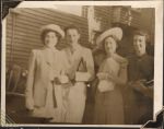 Medium shot of four women in casual wear, coats, hats and gloves. They are standing outside in front of a weatherboard building. Portrait, Circa 1945