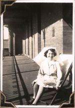 Long shot of a staff member sitting on a deckchair outside on the balcony of a building. The shadow of the verandah railings is visible on the ground. A Staff Member, Circa 1945