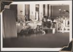 Long shot of a busy patient room with multiple beds and nurses stations. Some beds have patients in them and there are staff members in uniform throughout the room. Women's Hospital, Circa 1946