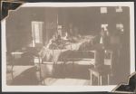 Long shot of a busy patient room with multiple beds and nurses stations. Some beds have patients in them and there are staff members in uniform throughout the room. Women's Hospital, Circa 1946