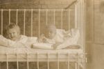 Medium shot of two patients in a cot outside posing for the camera. Infants in Bed, 1928