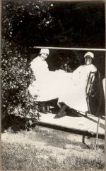 A long shot of two Nurses seated at a table outside posing for the camera. Nurses Enjoying the Sunshine, 1928