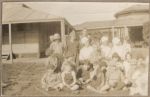 A long shot of three Nurses sitting with a large group of young patients outside possibly near the sea. Children Posing for the Camera, 1928