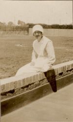 A long shot of a Nurse sitting outside on a brick wall beside a park. Portrait of a Nurse, 1928
