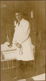 A long shot of a Doctor standing beside a bed with a small patient. He is holding a stethoscope. Doctor and Patient, 1928
